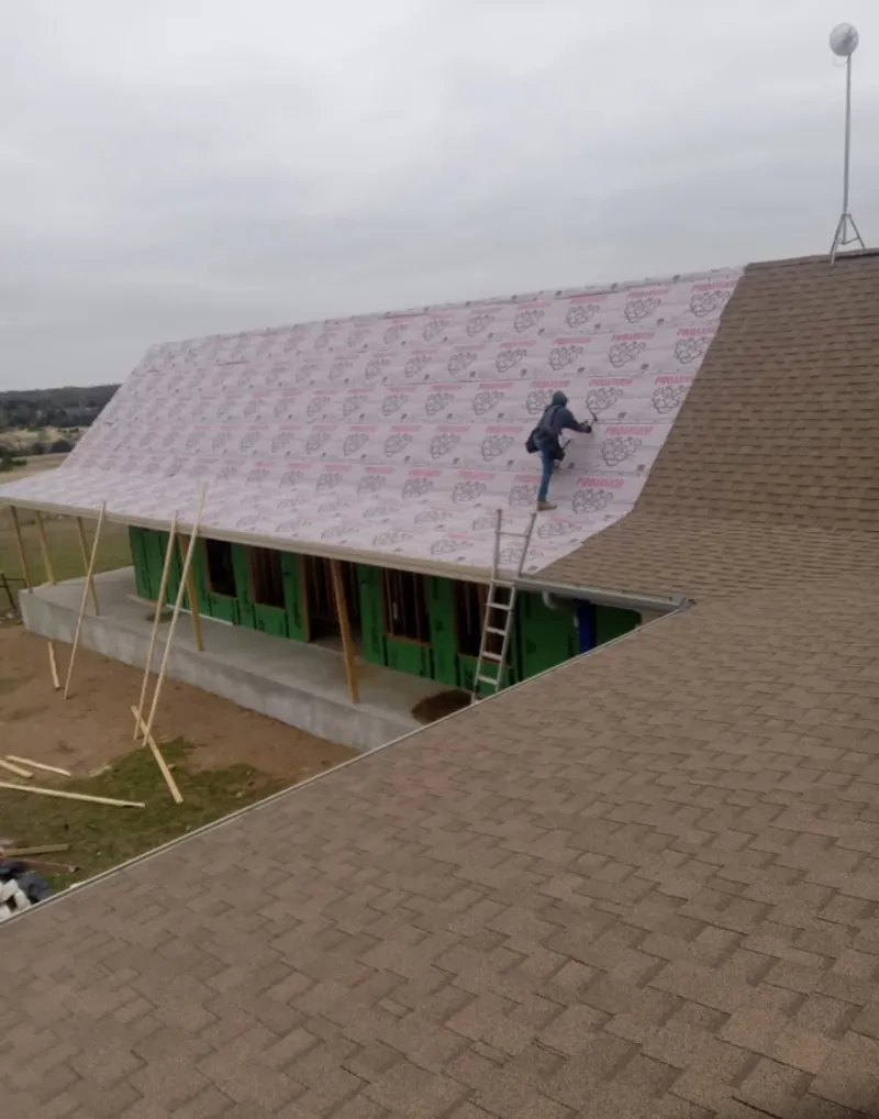 Worker preparing underlayment for a metal roof installation in Fairmont
